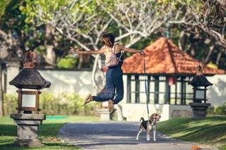 Woman jumping in mid-air while walking a dog