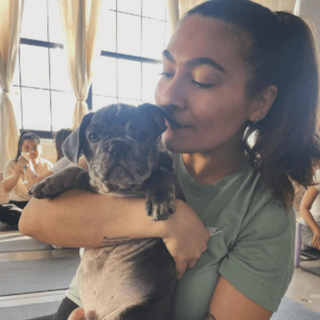 A 5 star review from a happy attendee. She is giving a puppy a kiss at Puppysphere's puppy yoga class in Brooklyn, New York City