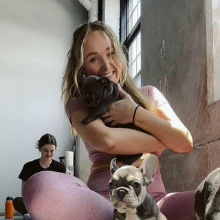 A woman surrounded by adorable puppy at the Puppysphere's puppy yoga class in NYC.