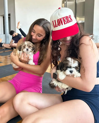 Two girls holding up puppies while other participants are performing yoga.