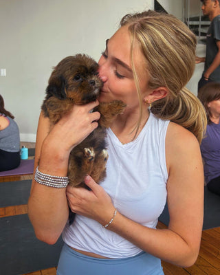 A girl kissing a Shih Tzu during Puppy Yoga & Bubbly