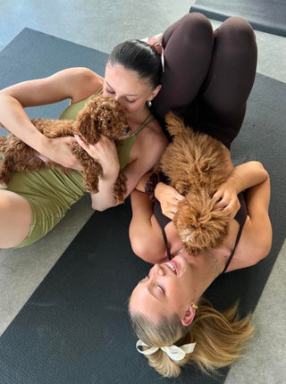 Two women enjoying puppy cuddles during a puppy yoga session in Chicago.