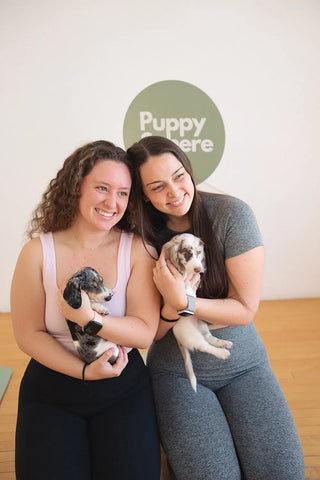 A pair of friends taking pictures at Wellness Puppy Yoga.